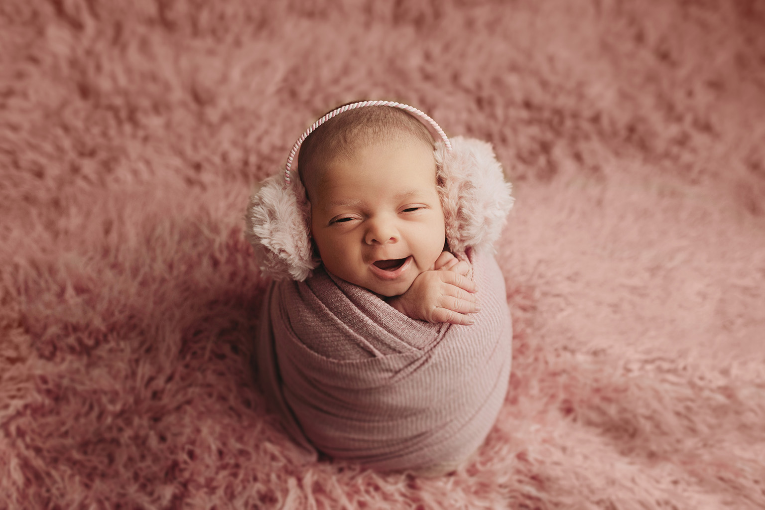 baby girl in potato pose on pink flokati with matching earmuffs