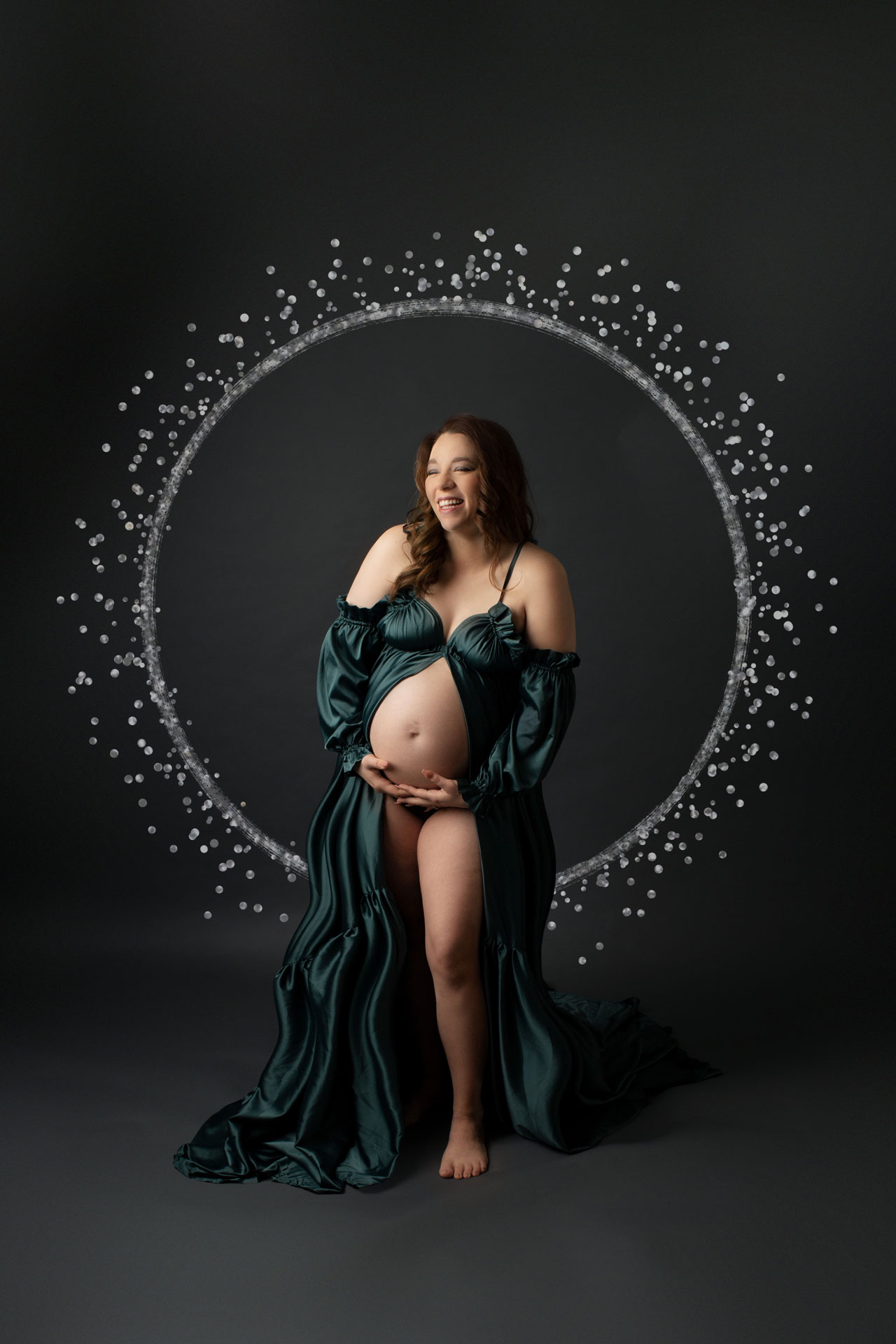 pregnant mom in teal silk gown with silver sparkle ring background