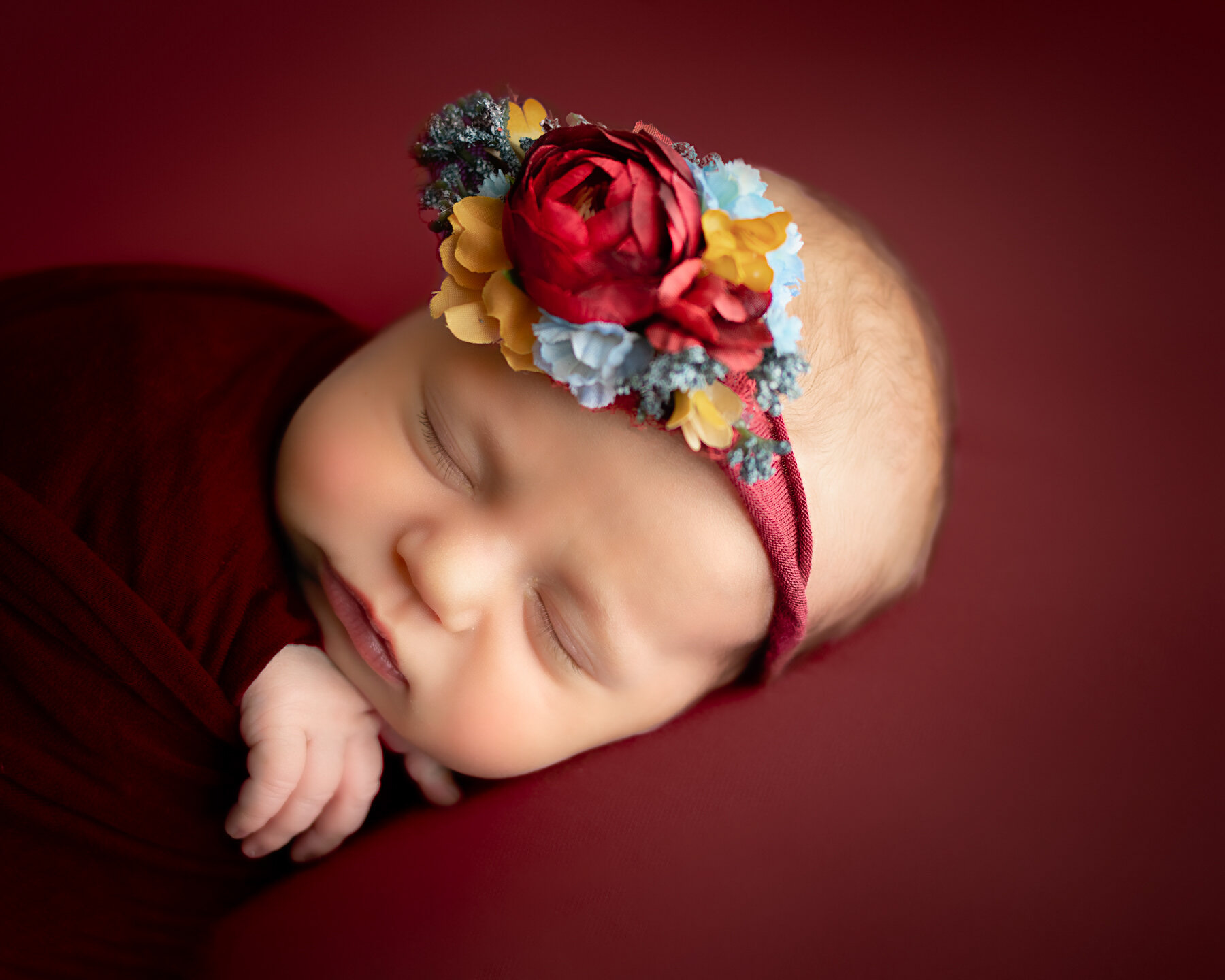 baby girl on burgundy with floral headband in newborn photography session in minneapolis minnesota