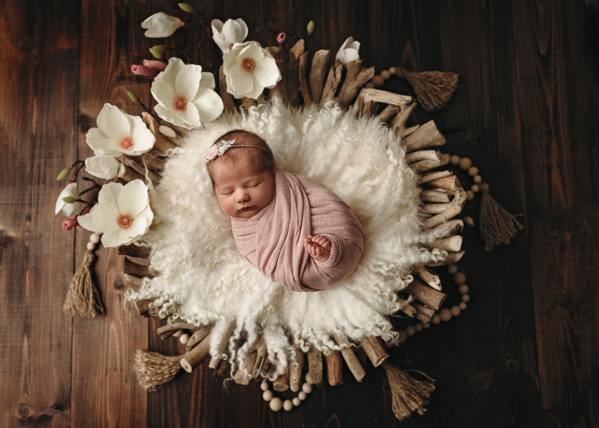newborn girl in driftwood bowl with magnolias and tassels in minneapolis newborn session