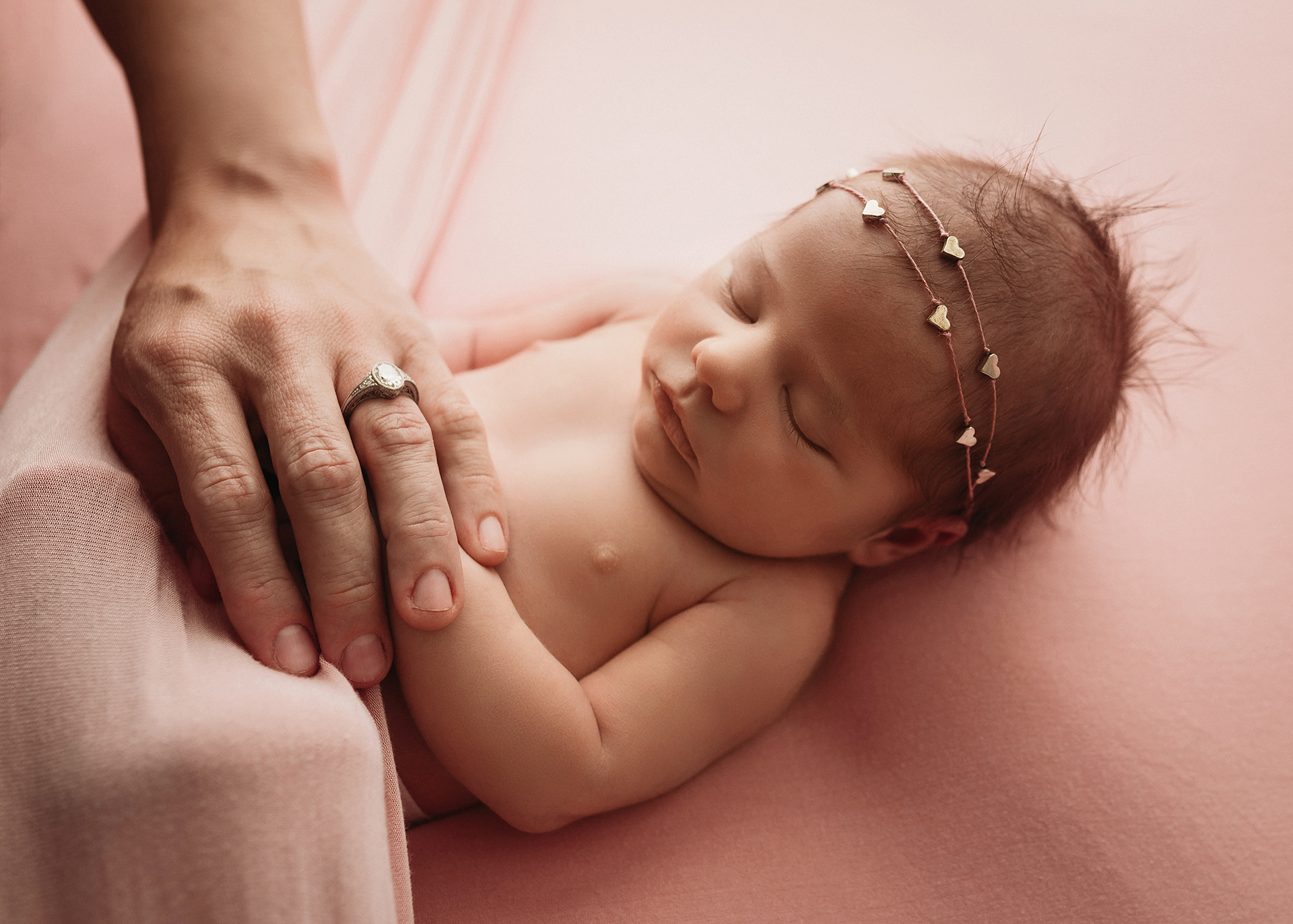 newborn girl tucked in with mom's hand on tummy for baby photography session in minneapolis
