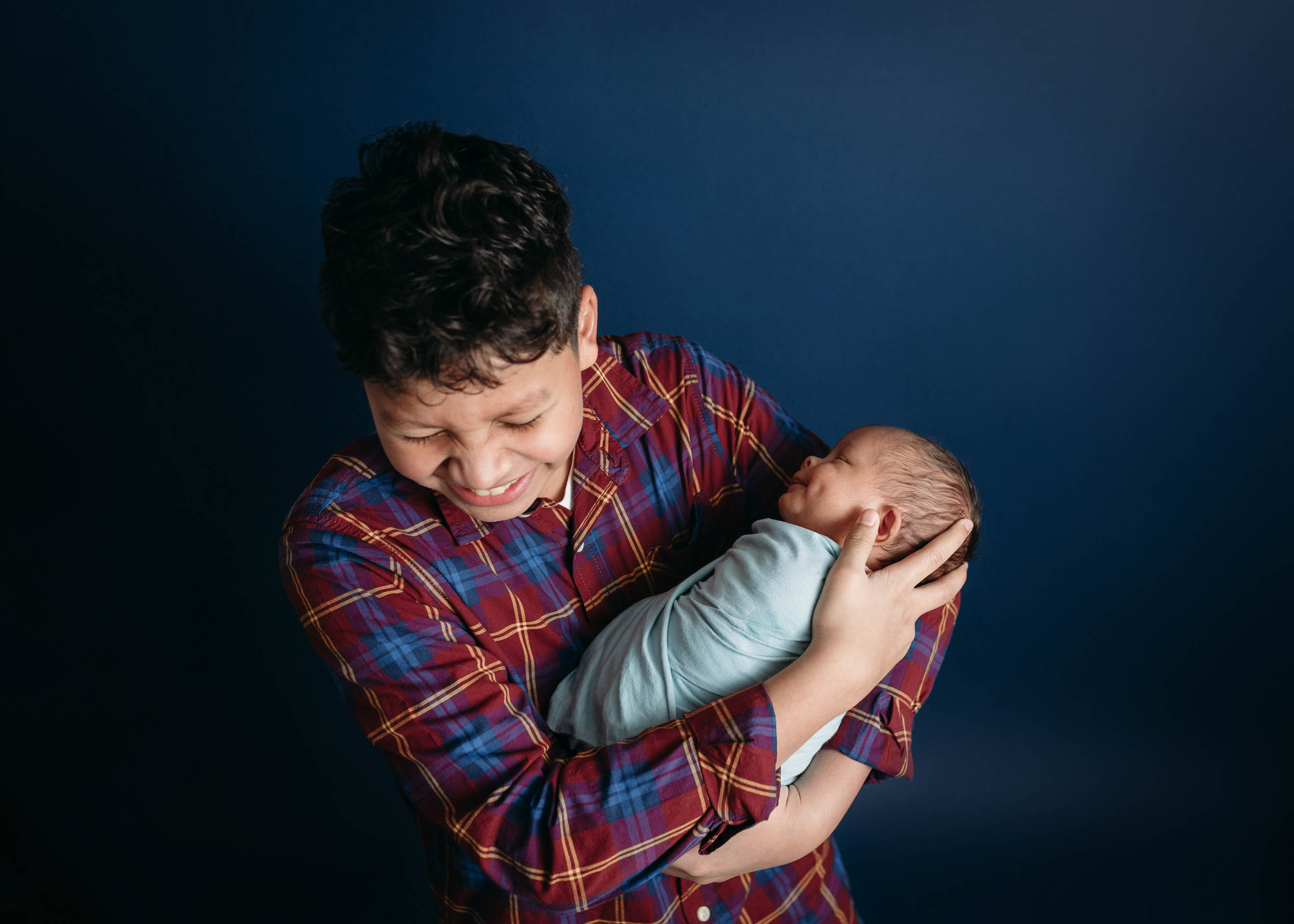 older brother holding newborn baby boy on navy background newborn photographer minneapolis minnesota