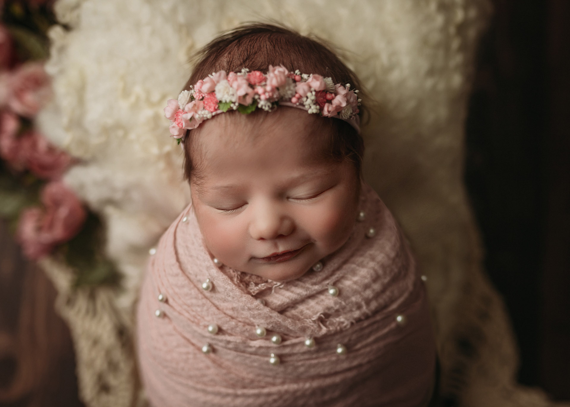 smiling newborn girl in pink pearls and flowers for newborn photography in kona Hawaii big island