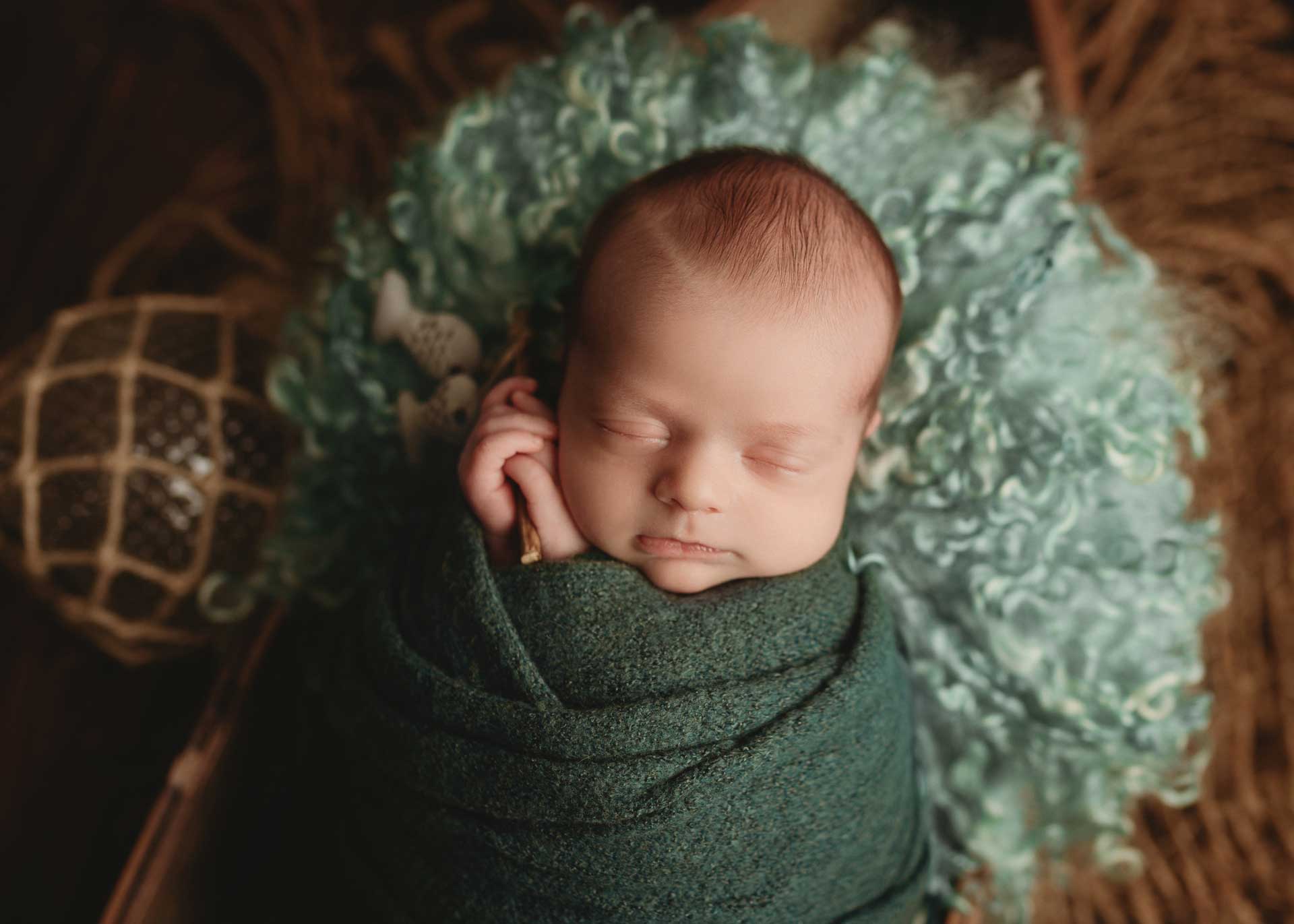 baby boy wrapped in sea green in boat prop with teal curly layer and fishing pole kona Hawaii newborn photographer